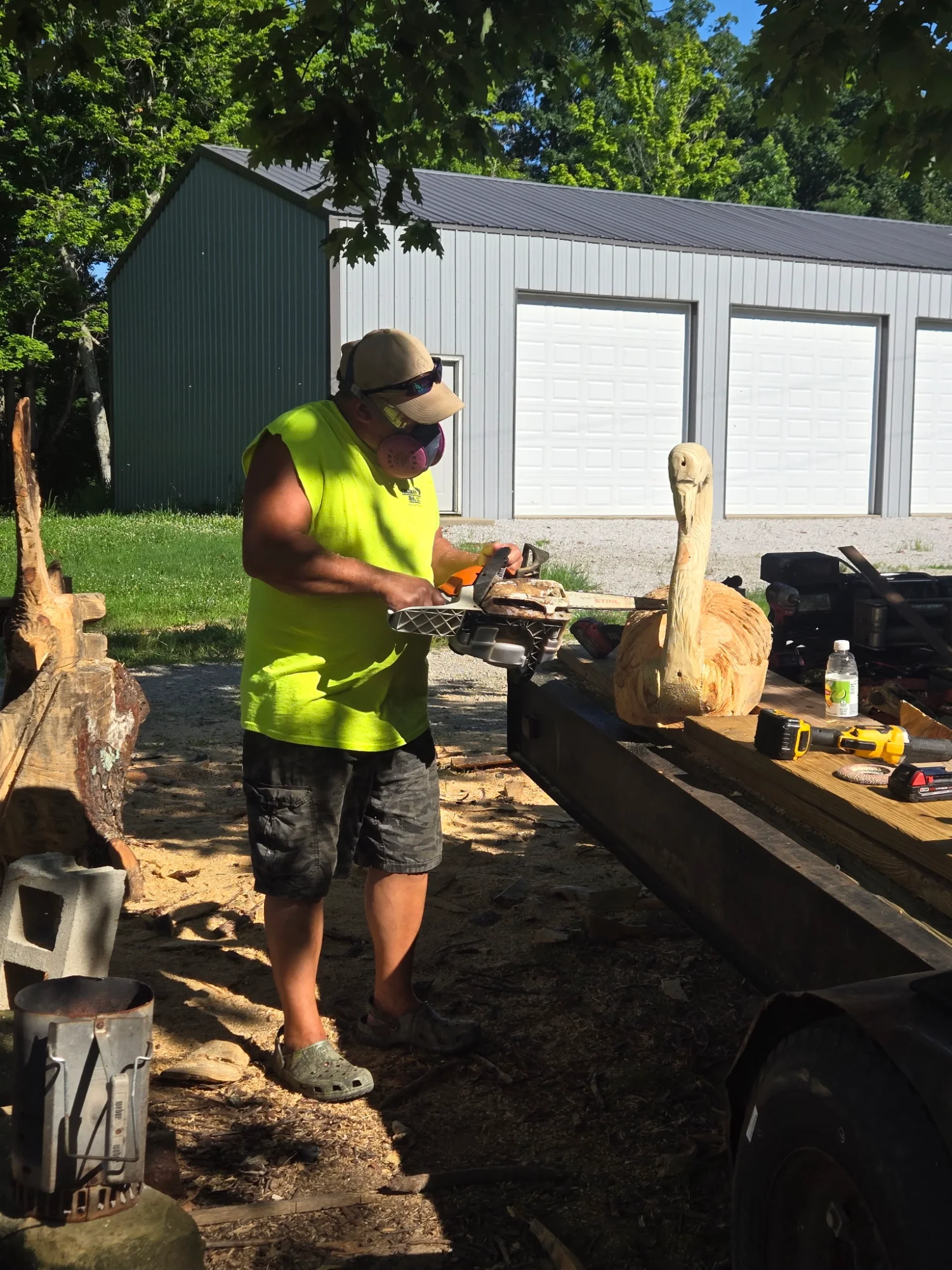 Gene carving outdoors in the summer, working on a pelican sculpture