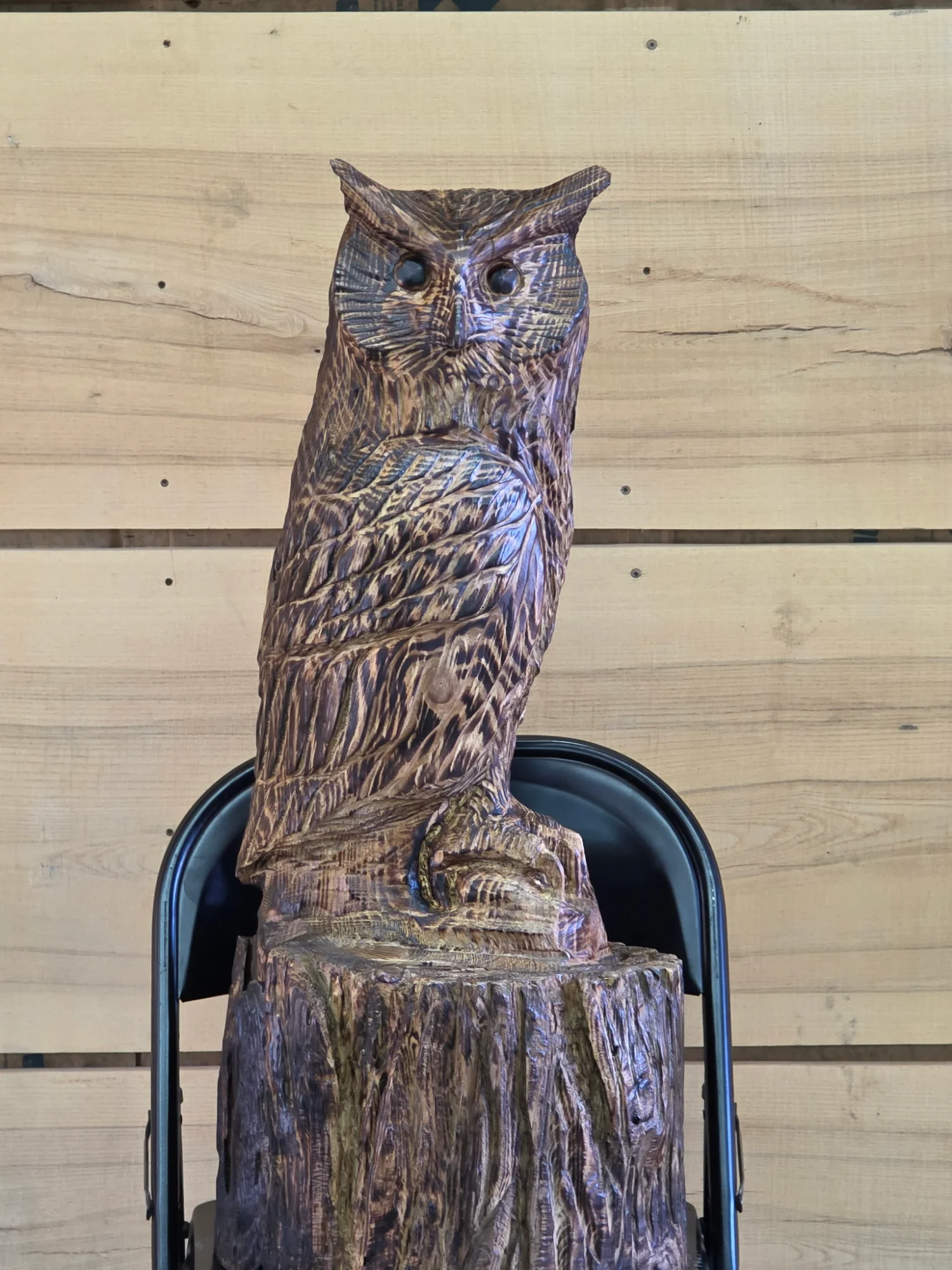 Great Horned Owl chainsaw carving with detailed feather texture perched on tree stump